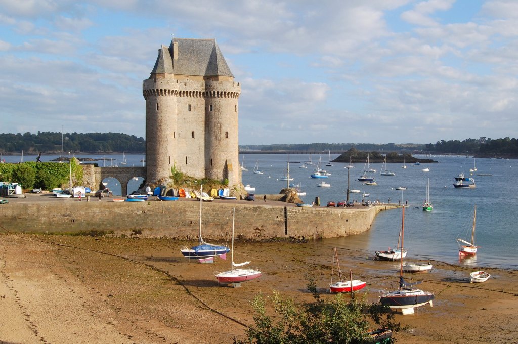 Uma foto da torre Solidor, que se ergue sobre a água perta de uma praia, e cercada por vários veleiros pequenos.